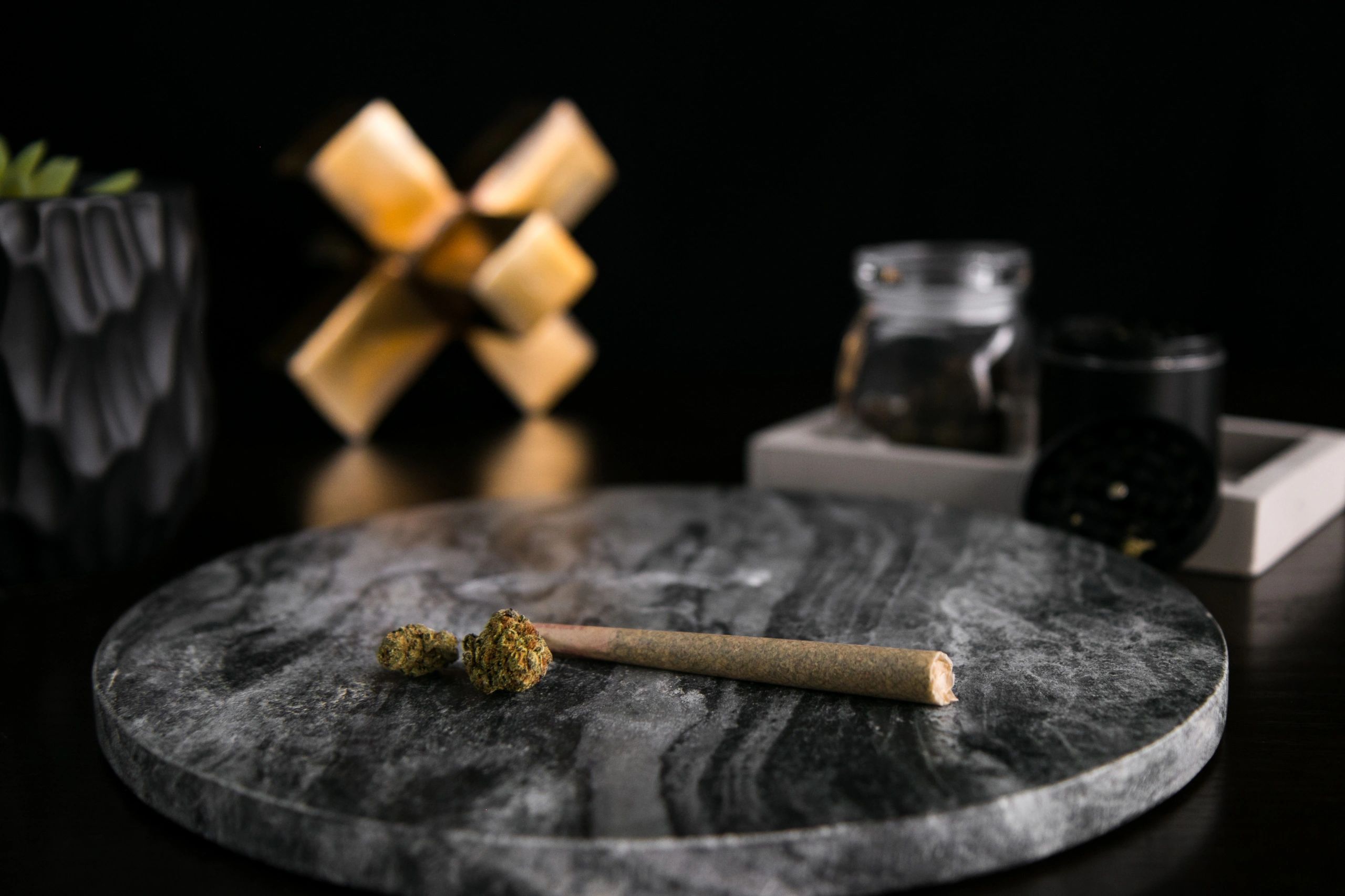 Cannabis buds and joint on dark marble surface